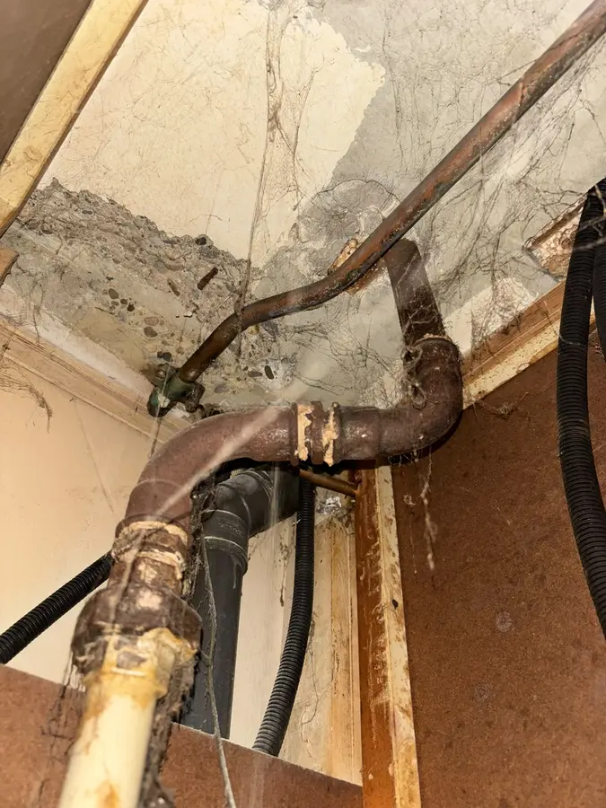 Blootgelegde oude leidingen achter een weggehaalde wand