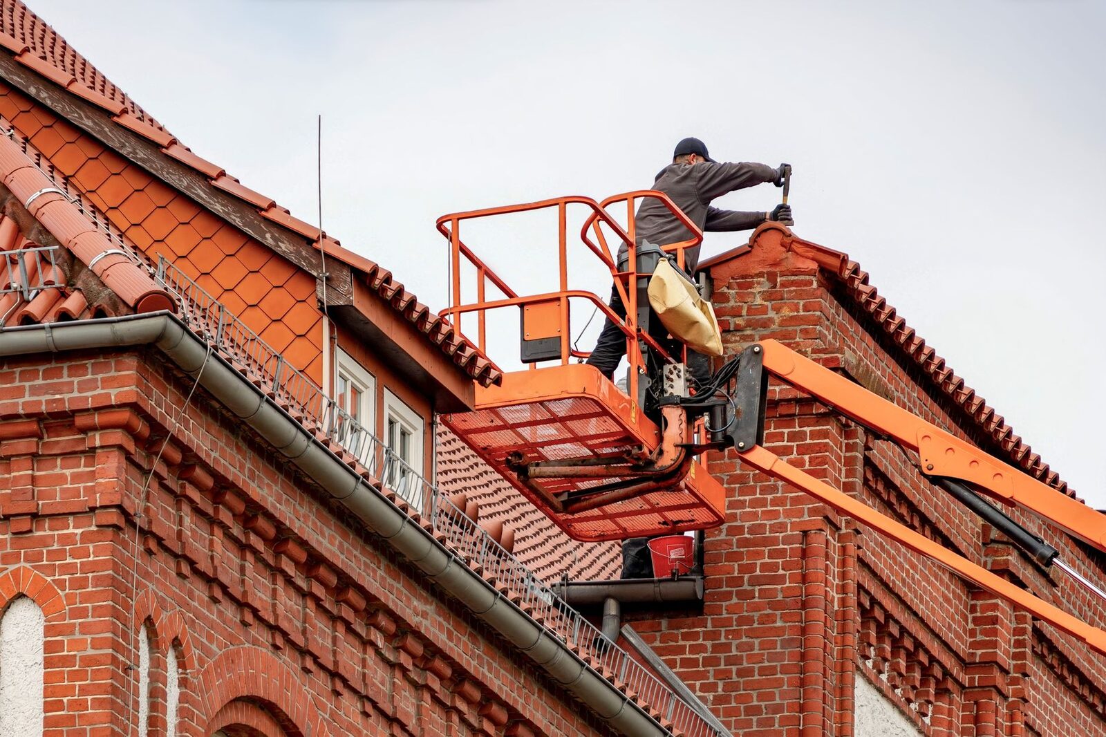 Dakdekker in een hoogwerker controleert een pannendak